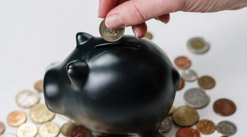 person putting coin in a piggy bank